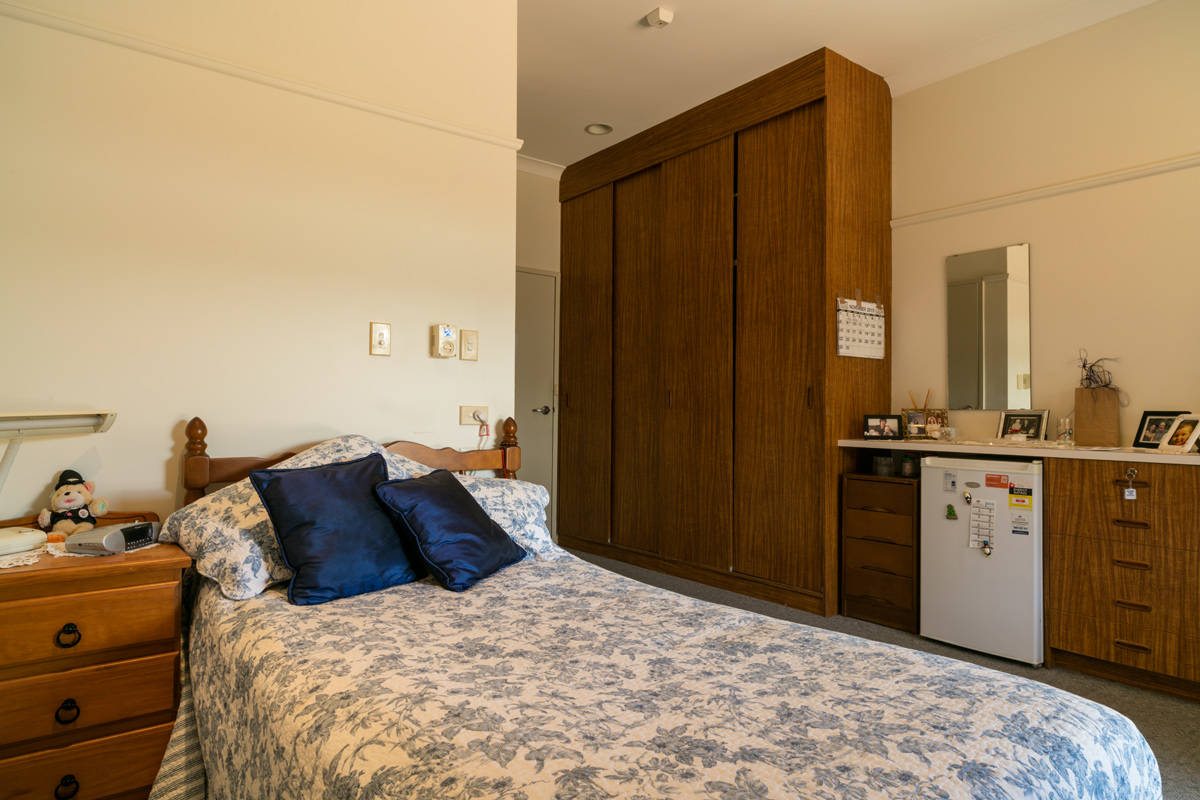 A residential room found at Whiddon Bourke, featuring a large wardrobe space and a mini fridge.