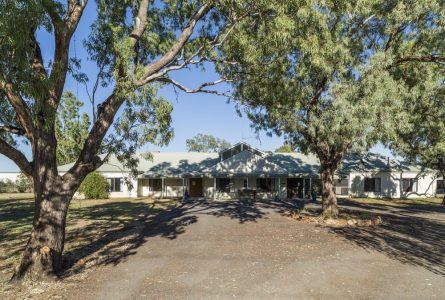 A front view of Whiddon's Walgett Aged Care home, surrounded by tall native trees.