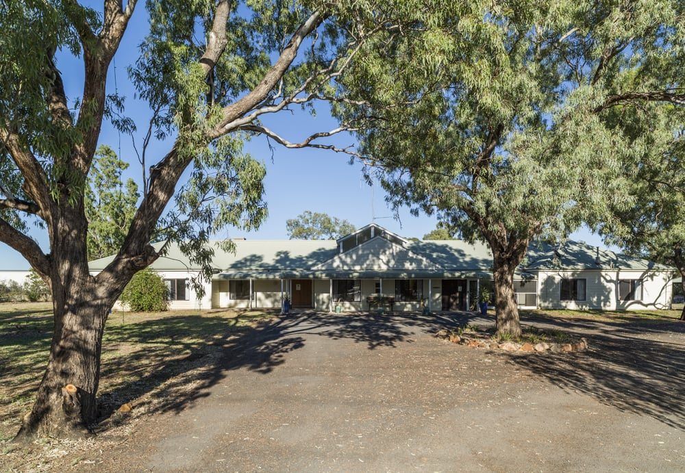 A front view of Whiddon's Walgett Aged Care home, surrounded by tall native trees.