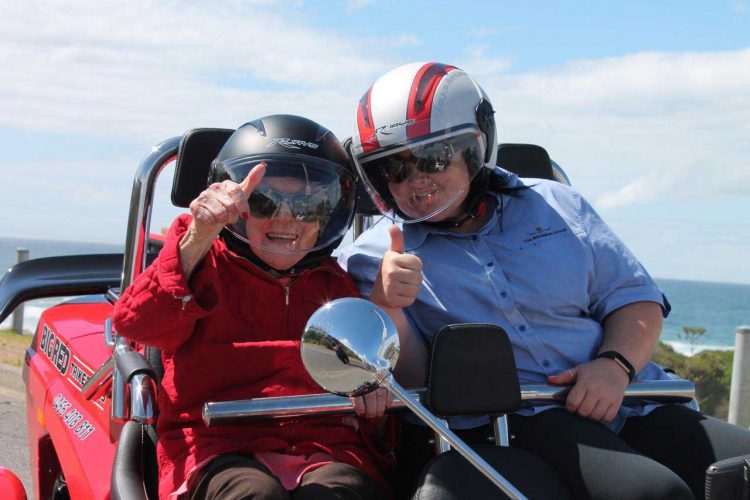 Bette, a resident at Whiddon, enjoying a motorcycle ride by the beach with a Whiddon carer.