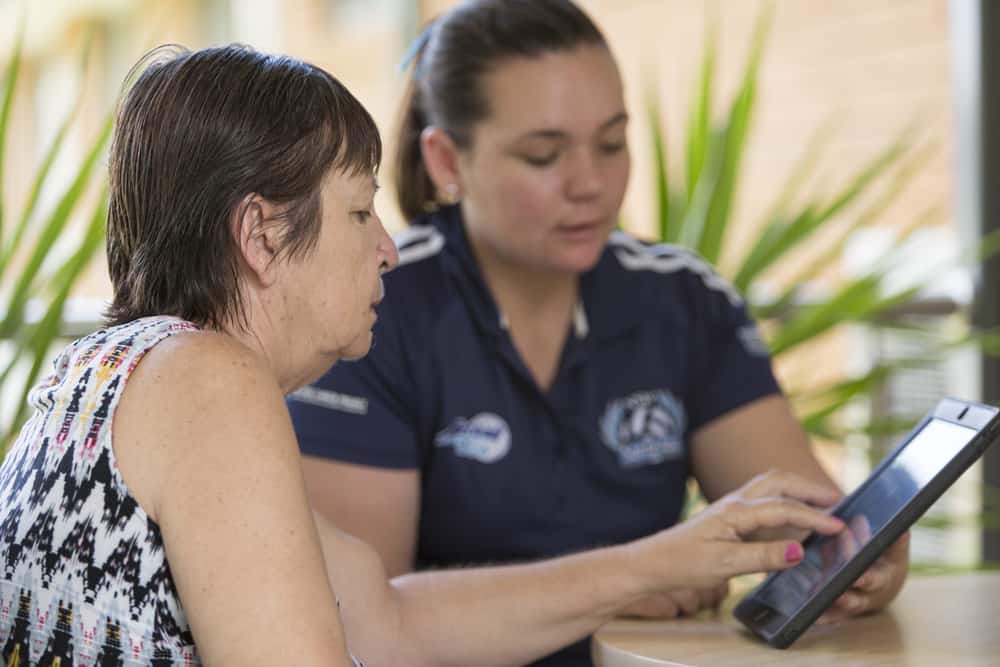 A resident and carer playing with an iPad at Whiddon's aged care home in Newcastle, NSW.