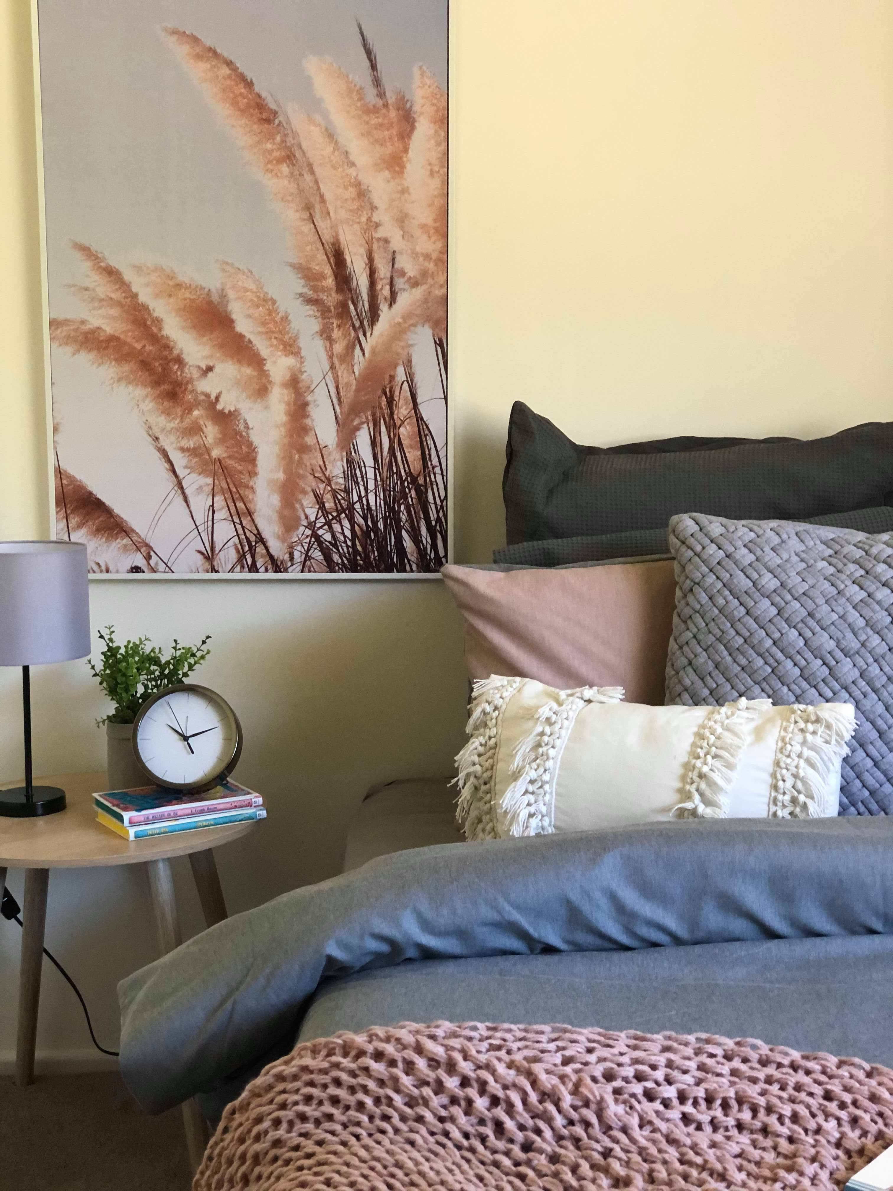 A comfortable bed with pastel coloured bedding and modern bedside table inside Whiddon Laurieton retirement village.