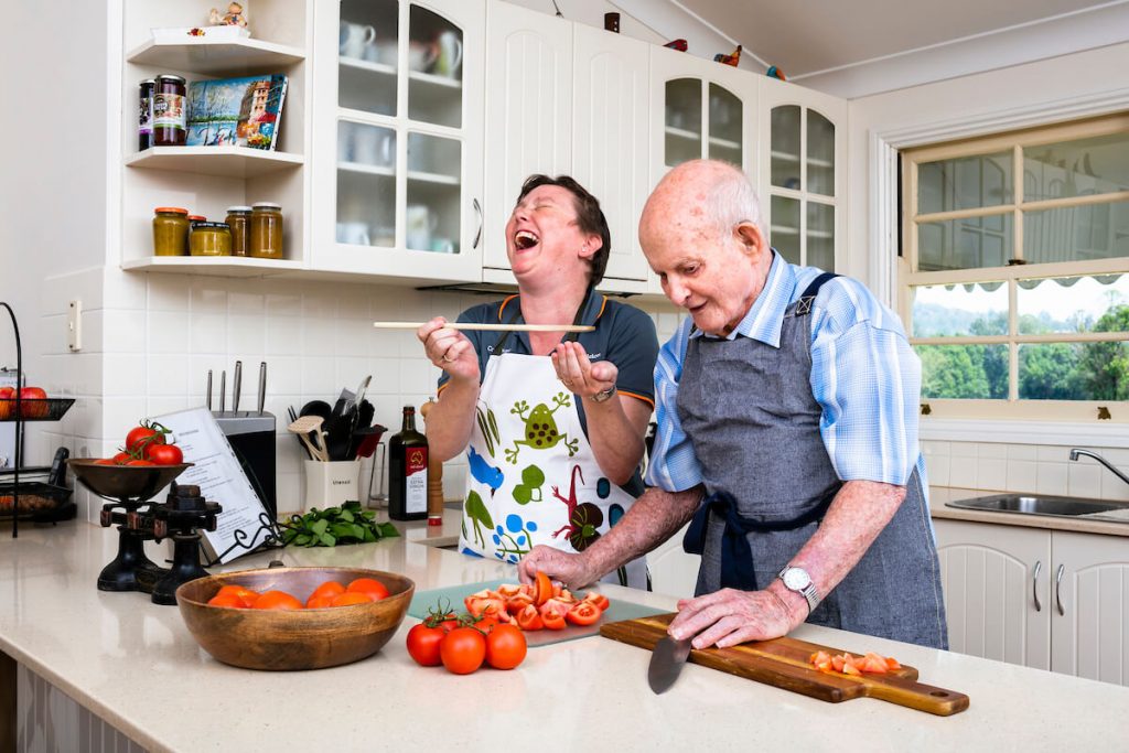 older man cooking at home with care worker