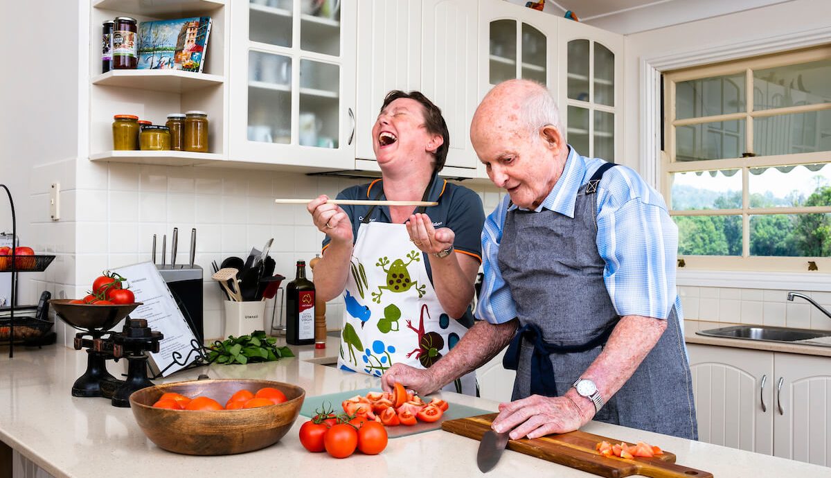 older man cooking at home with care worker